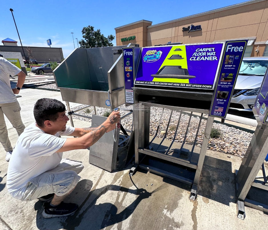 Feel Great Car wash employees showing off their carpet floor mat cleaner that visitors can use for free cleaning