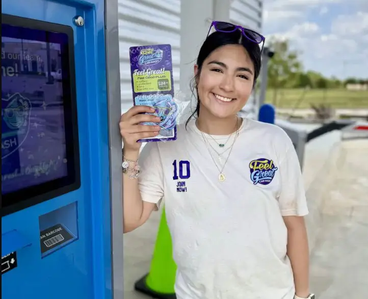 A Feel Great Car Wash Employee smiling and showing promotional material for a car wash