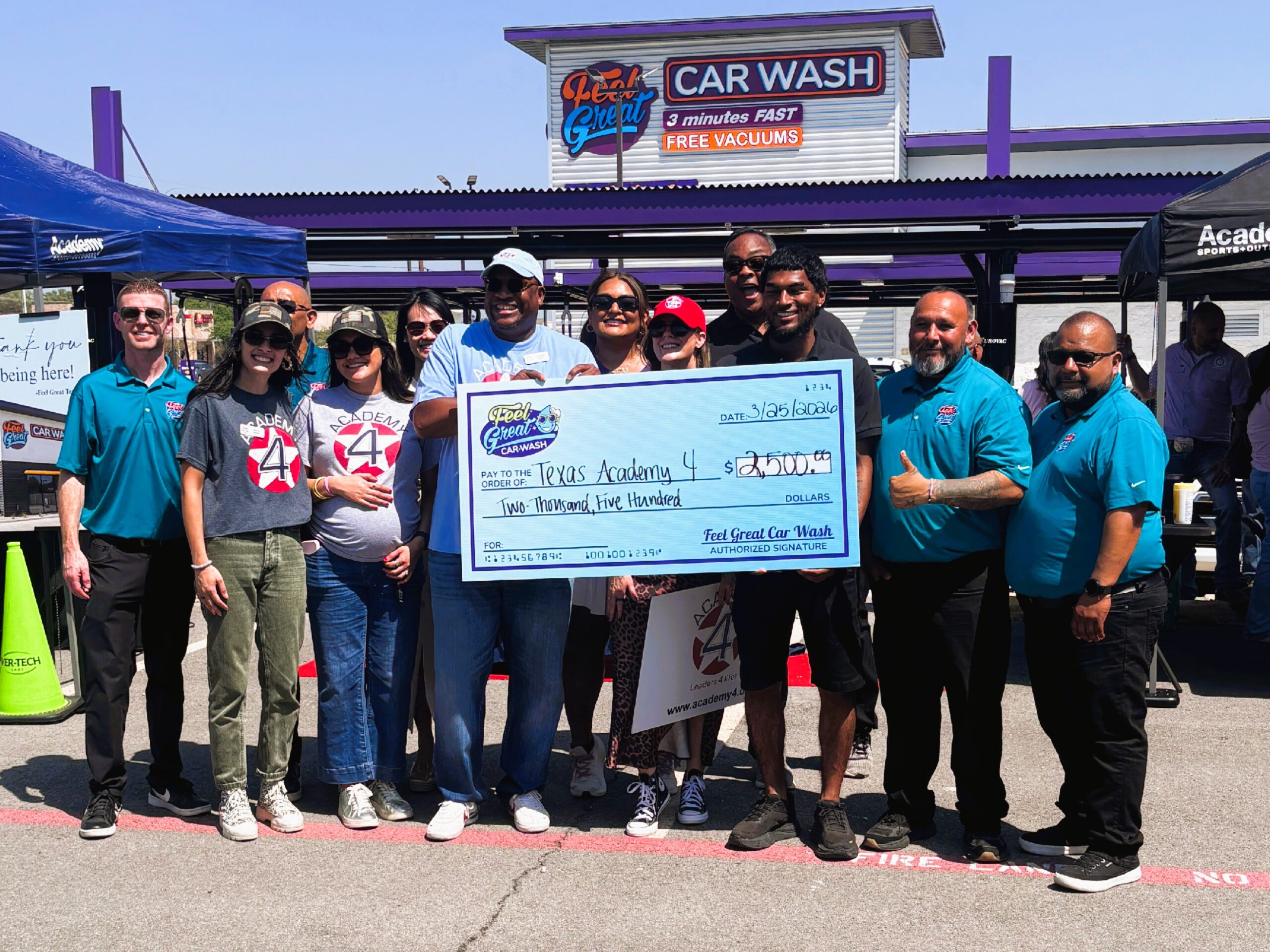 Feel Great Car Wash handing a check to Texas Academy 4 for two thousand five hundred dollars as a donation.